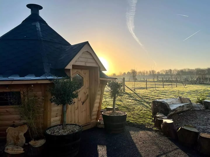 BBQ log cabin in a field at sunrise